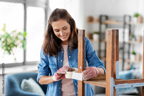 Foto repair, diy and home improvement concept - happy smiling woman sticking adhesive