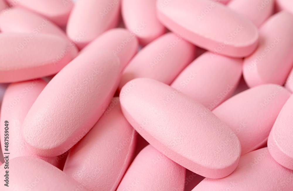 Closeup heap of pink supplement pills for he concept of beauty and healthcare
