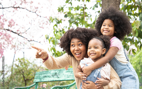 Africa American family doing activity and pointing something on an autumns day in the park. They have bright smiles and happiness.