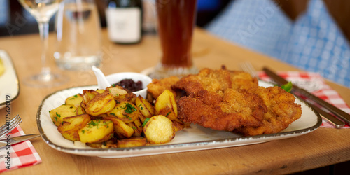 Bild auf Leinwand Saftiger Wiener Schnitzel vom Kalb mit wellen Panade und Bratkartoffeln auf schö