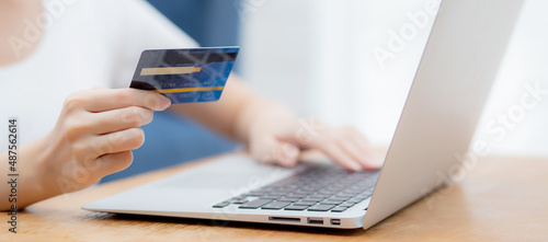 Hand of young woman holding credit card buying shopping online with laptop computer, girl purchase and payment on internet, commerce and e-business, transaction for finance, business concept.