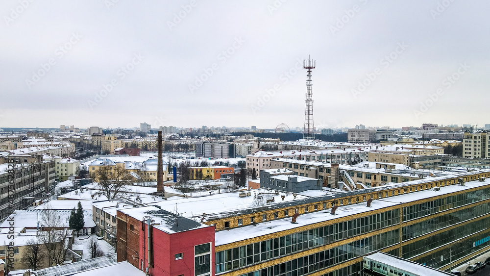 Beautiful top view of cityscape with tv tower, ferris wheels, factory and buildings in winter.
