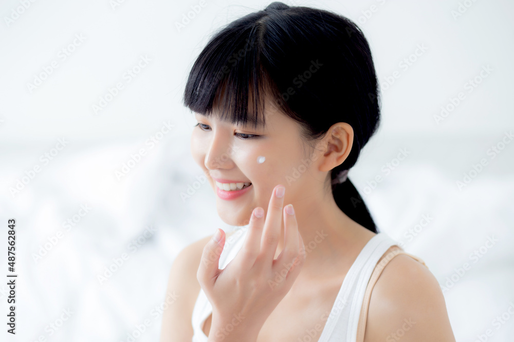 Beautiful young asian woman happy applying cream or lotion with moisturizer to skin on face, beauty asia girl applying skincare touch facial with cosmetic makeup, skin care and health concept. Beautiful young asian woman happy applying cream or lotion with moisturizer to skin on face, beauty asia girl applying skincare touch facial with cosmetic makeup, skin care and health concept.