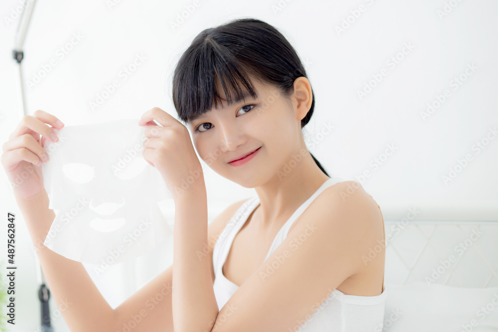 Beautiful young asian woman holding sheet facial mask for skin care and treatment, beauty girl showing sheet face mask with fun and relax at home, skincare and therapy for smooth, health and wellness. Beautiful young asian woman holding sheet facial mask for skin care and treatment, beauty girl showing sheet face mask with fun and relax at home, skincare and therapy for smooth, health and wellness.