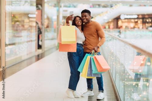 Happy black couple taking selfie after shopping at mall