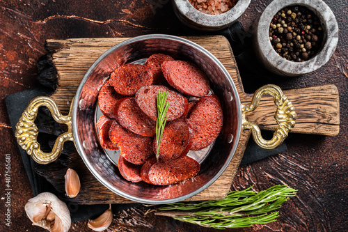 Turkish fried sausage sucuk in a pan. Dark background. Top view photo