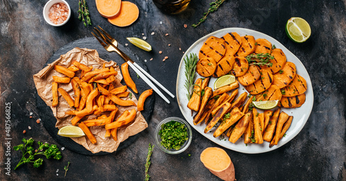 Sweet potato fries with herbs on dark background. Long banner format. top view
