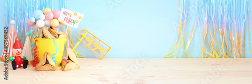 Purim celebration concept (jewish carnival holiday) over purple wooden table and pastel blue background photo