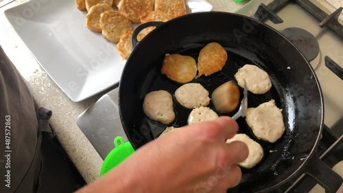 Top view on woman hand tunrning pancakdes frying on a cast-iron pan