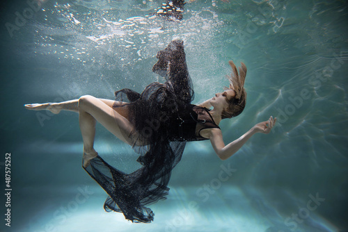 a woman in a black dress under water