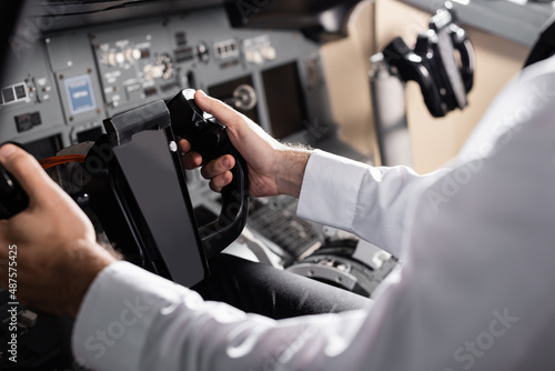 partial view of pilot using yoke in airplane simulator.
