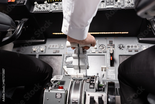Fotografija partial view of pilot using thrust lever in airplane.