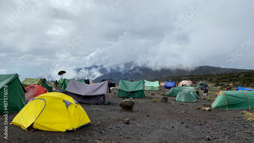Multi-colored tents stand in the mountains. Beautiful mountain landscape. Climbing Kilimanjaro, Africa.