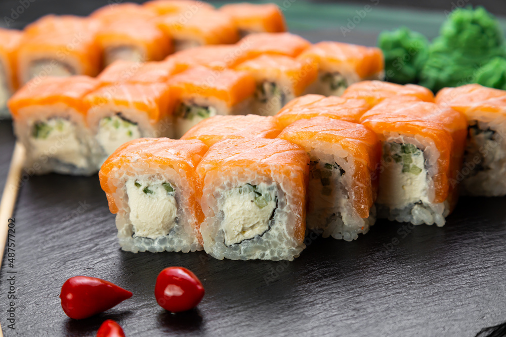 sushi rolls laid out on a dark background decorated with bamboo leaves and chopsticks sushi rolls laid out on a dark background decorated with bamboo leaves and chopsticks