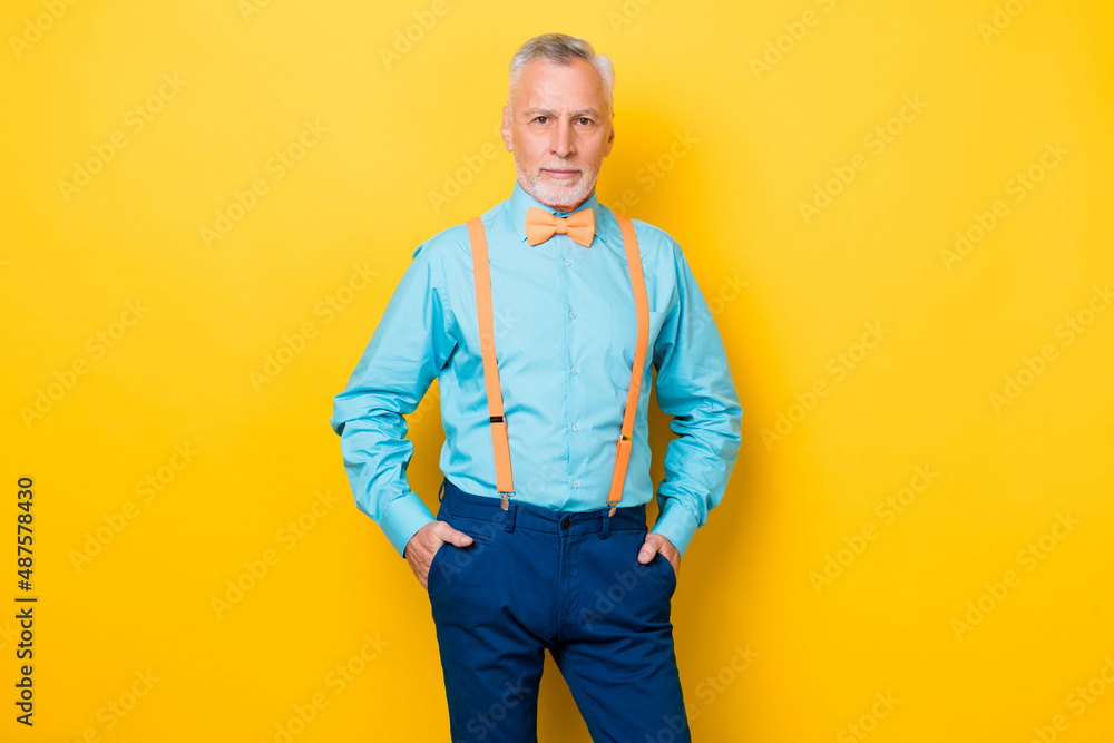 Photo of old grey hairdo man wear teal shirt suspenders bow tie isolated on yellow color background Photo of old grey hairdo man wear teal shirt suspenders bow tie isolated on yellow color background