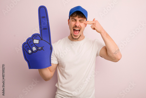 young cool man looking unhappy and stressed, suicide gesture making gun sign. number one fan concept