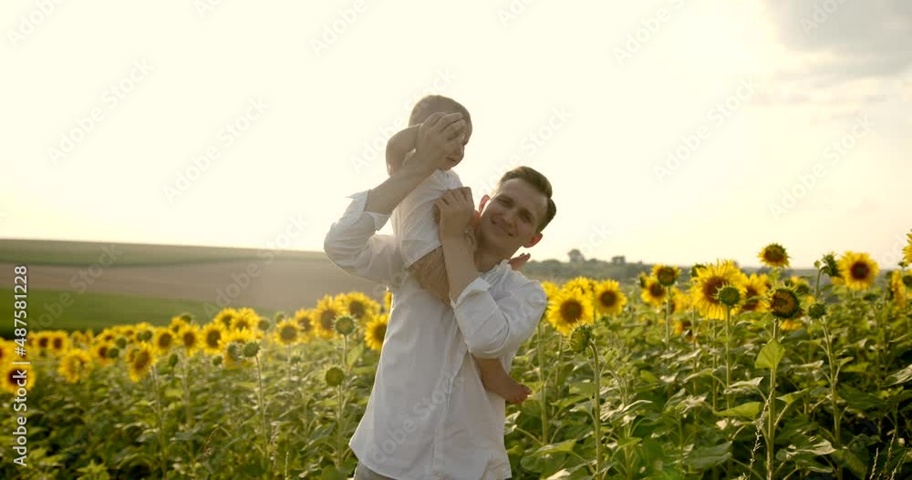 Father holding his little son standing in sunflower field Father holding his little son standing in sunflower field