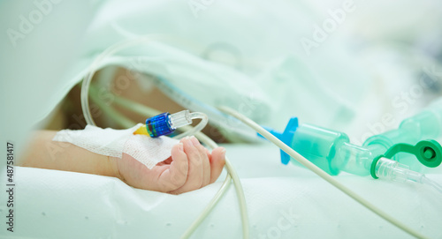 Children surgery. Small hand with saline intravenous dropper during surgical operation in hospital