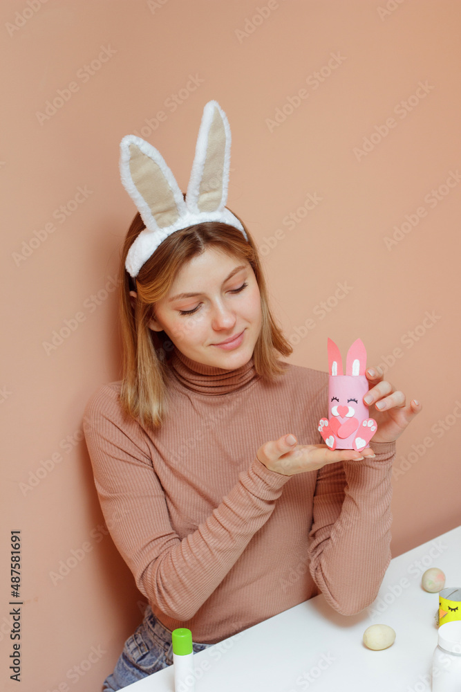 Beautiful young woman with bunny ears making Handmade Easter decoration little rabbit DIY. Reuse concept art from roll. Beautiful young woman with bunny ears making Handmade Easter decoration little rabbit DIY. Reuse concept art from roll.