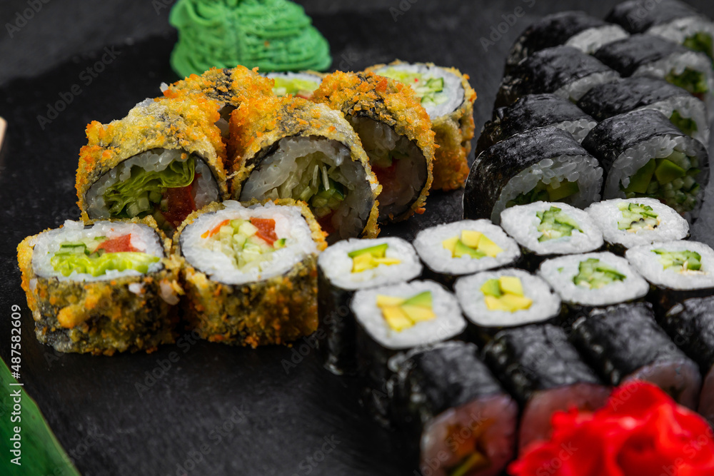 sushi rolls laid out on a dark background decorated with bamboo leaves and chopsticks sushi rolls laid out on a dark background decorated with bamboo leaves and chopsticks
