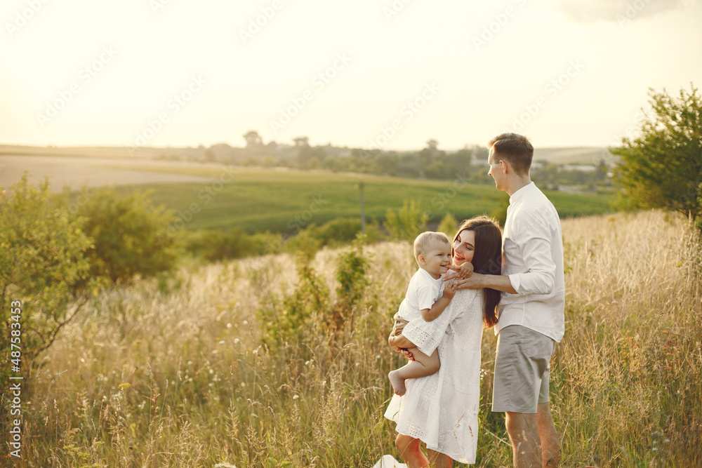 Mother, father and son in white clothes walking on the field Mother, father and son in white clothes walking on the field