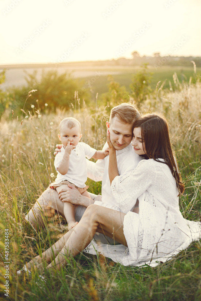 Mother, father and son in white clothes on the field posing for a photo Mother, father and son in white clothes on the field posing for a photo