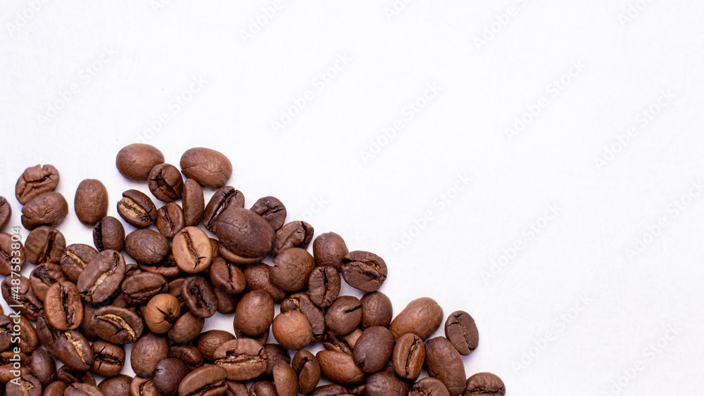 Obraz premium fragrant beans from the coffee tree in medium roast lie on a white background with a place for text
