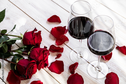 romantic dinner. Two glasses of wine with roses and petals.