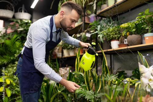 a man in a flower warehouse caring for potted plants