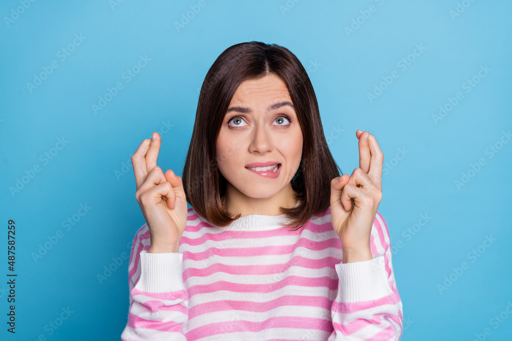 Photo of doubtful unsure uncertain woman wear striped sweater fingers crossed empty space isolated blue color background Photo of doubtful unsure uncertain woman wear striped sweater fingers crossed empty space isolated blue color background