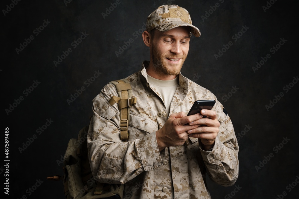 White military man wearing uniform smiling and using cellphone White military man wearing uniform smiling and using cellphone