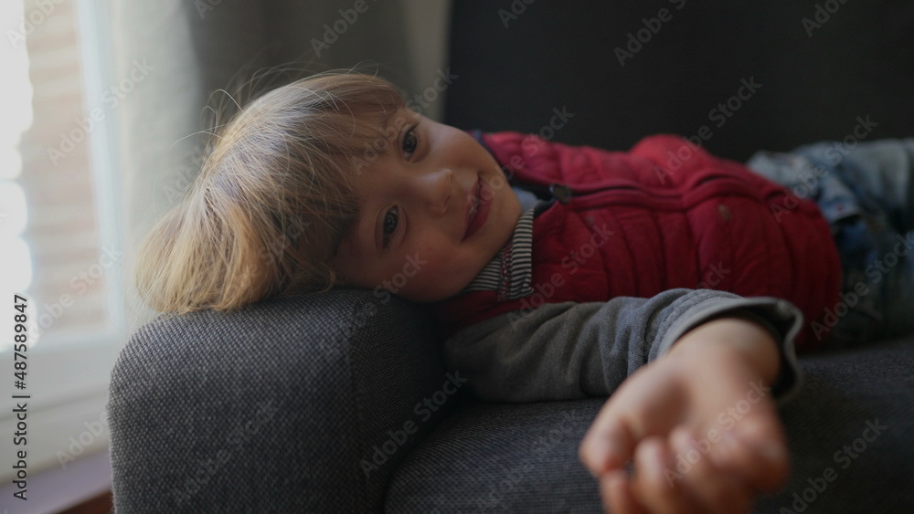 Fototapeta premium Cute child boy lying on sofa looking at camera
