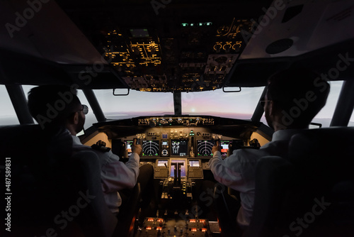 Foto back view of professionals piloting modern airplane.