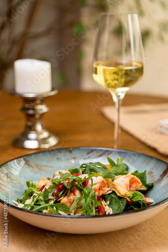 fresh salad served with a glass of wine. served table
