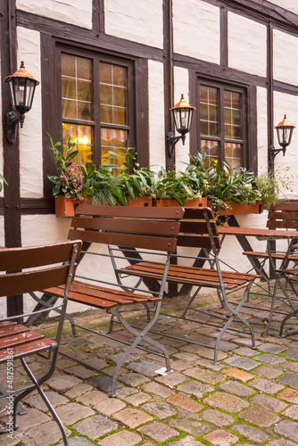Sidewalk cafe decoration. Outdoor cafe in old town in Germany. Flower pot and street lantern on house facade. Half-timbered decorated house in Nuremberg. Medieval architecture.