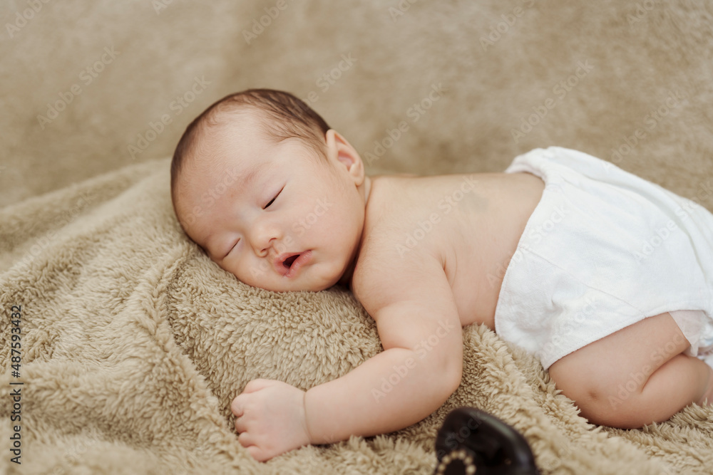close-up photo of face of an Asian newborn sleeping happily on a brown carpet. close-up photo of face of an Asian newborn sleeping happily on a brown carpet.