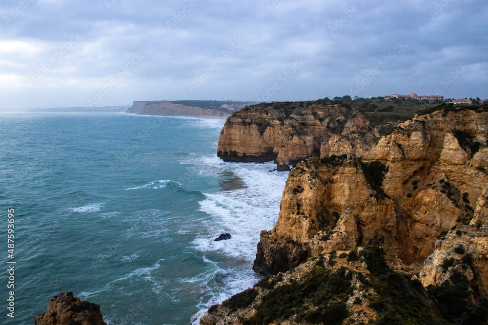 Scenery of Algarve, Lagos in stormy weather with waves crashing against the cliffs	
