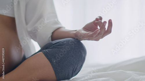 Close Up Asian pregnant wife sitting in meditation in the bedroom.