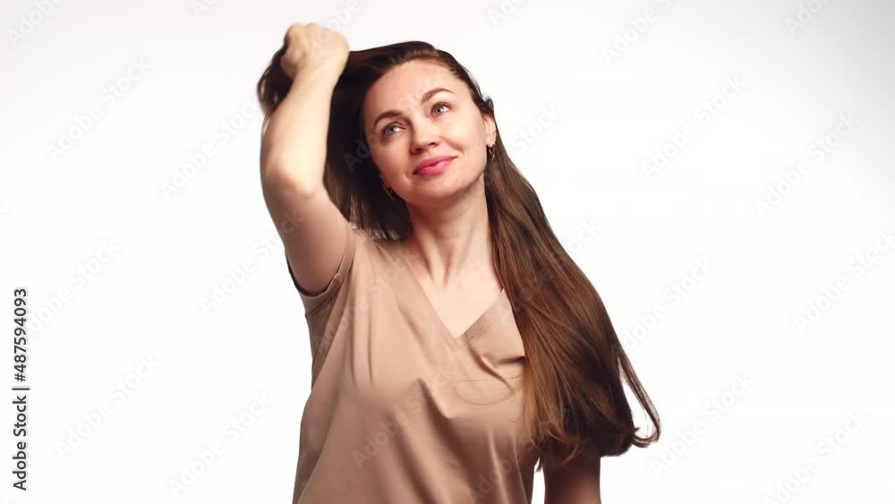 Attractive woman smile and combs hair with hand, going through them beautifully, front view. Woman long brown hair combs head with palm of hand, sorting through strands Attractive woman smile and combs hair with hand, going through them beautifully, front view. Woman long brown hair combs head with palm of hand, sorting through strands
