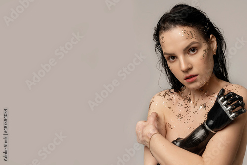 Beauty disabled Woman with prosthetic arm. Natural Clean Skin Nature Makeup with glitter Fresh Spa Women's Beautiful Cosmetic Portrait. Beauty variety. Isolated on beige background. Copy space