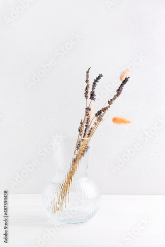 Dried flowers in a vase on a table against a light background. Space for text