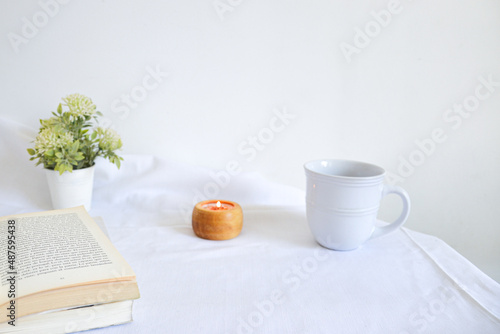 reading moment with candle, cup of tea and flowers