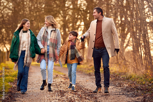 Family Holding Hands On Walk Through Autumn Countryside Together