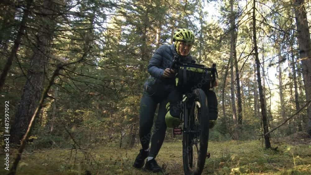 The woman travel on mixed terrain cycle touring with bike bikepacking outdoor. The traveler journey with bicycle bags. Stylish bikepacking, bike, sportswear in green black colors. Magic forest park. The woman travel on mixed terrain cycle touring with bike bikepacking outdoor. The traveler journey with bicycle bags. Stylish bikepacking, bike, sportswear in green black colors. Magic forest park.