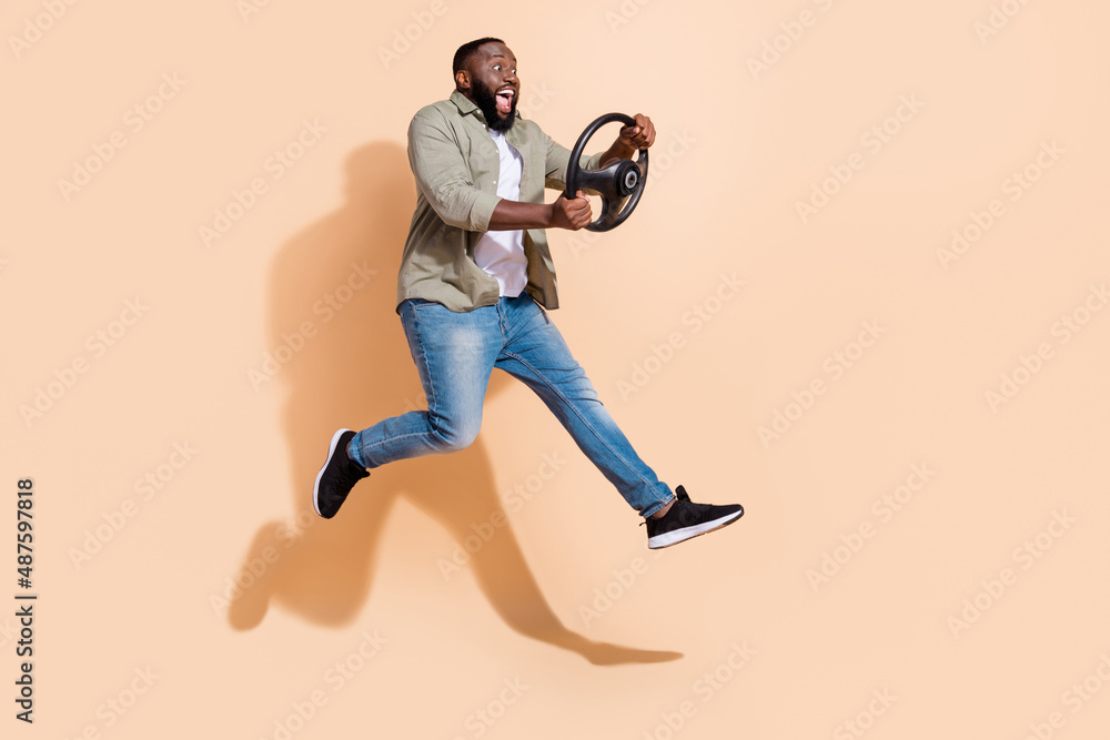 Full length impressed millennial brunet guy run drive wear shirt jeans footwear isolated on beige background