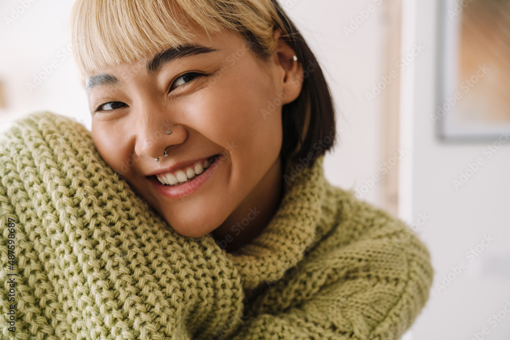 Asian girl with piercing smiling at camera while resting at home Asian girl with piercing smiling at camera while resting at home
