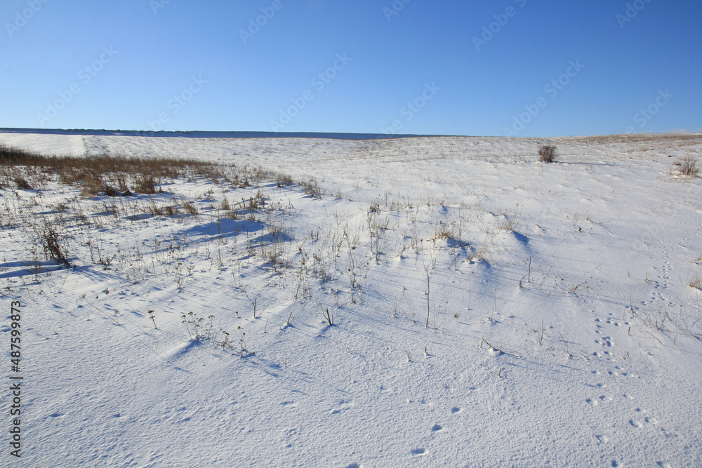 Snow field under blue sky, footprints in the snow