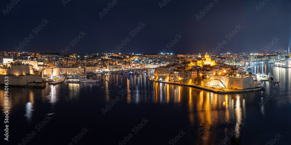 Panoramic view of Three cities in Malta at night. Photo taken from Valletta, Malta. The Grand Harbour illuminated at night.