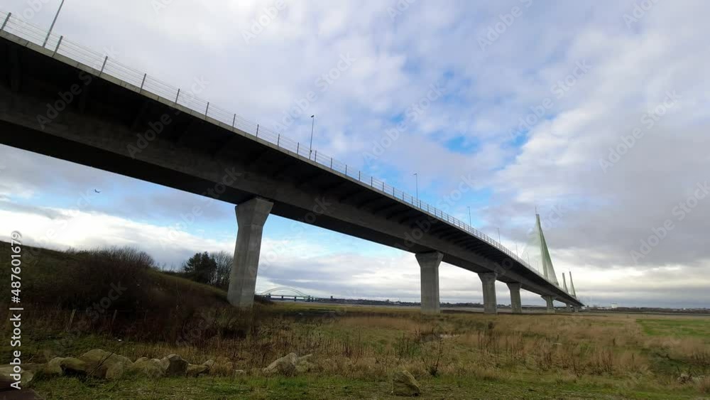 Speeding time lapse clouds passing over rural countryside marshland suspension bridge Speeding time lapse clouds passing over rural countryside marshland suspension bridge