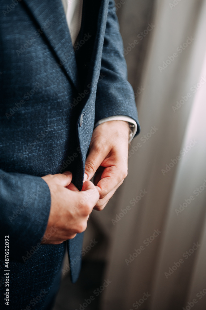 Mens hands fasten the buttons of a jacket 3827.